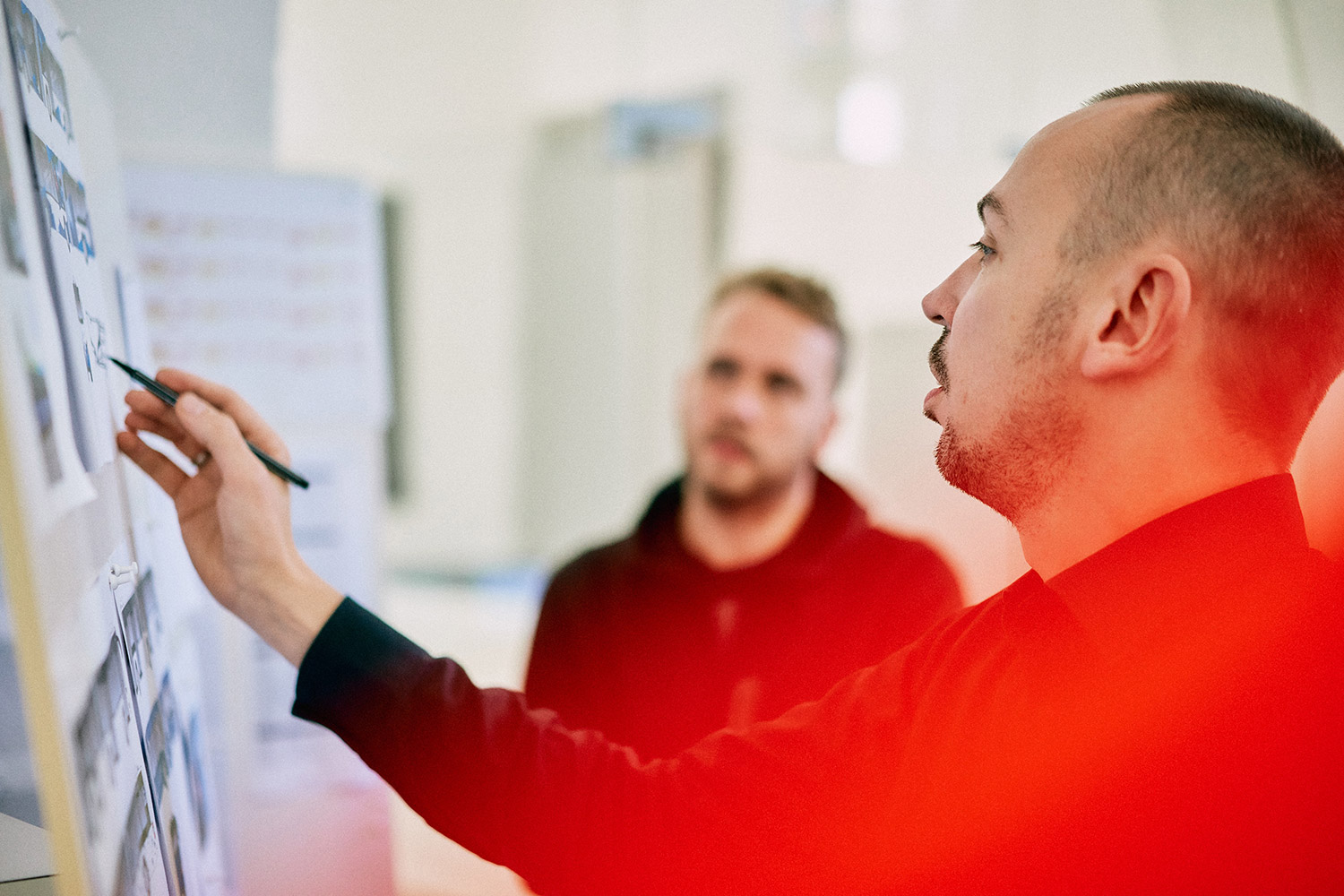 Boris Schmelter erklärt an einem Whiteboard mit Notizen, während eine andere Person aufmerksam zuhört.